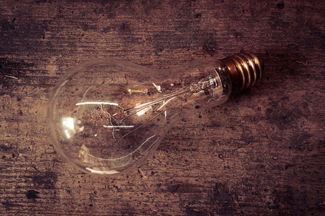 Traditional glass filament light bulb lying on a wooden surface