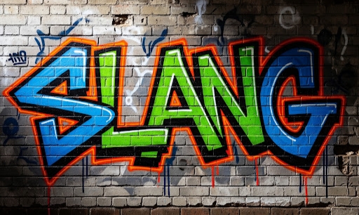 A grey-white brick wall on which is sprayed the word "slang" graffiti stile in blue and green letters outlined in orange